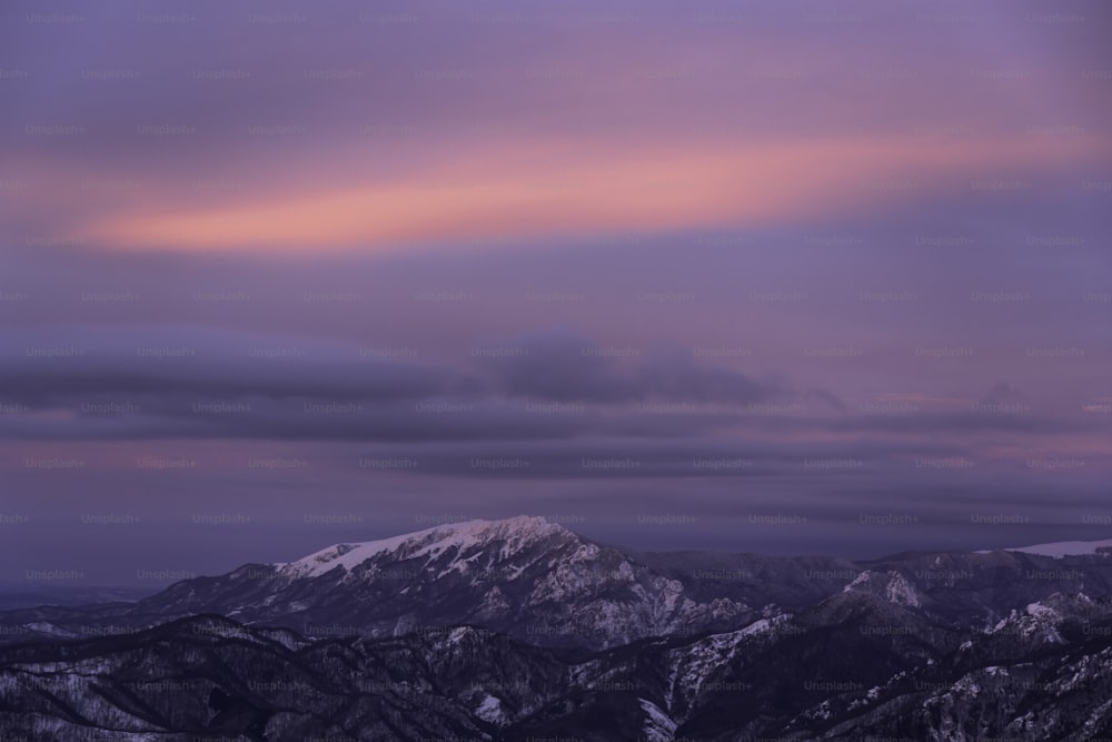 a view of a mountain range with a pink sky