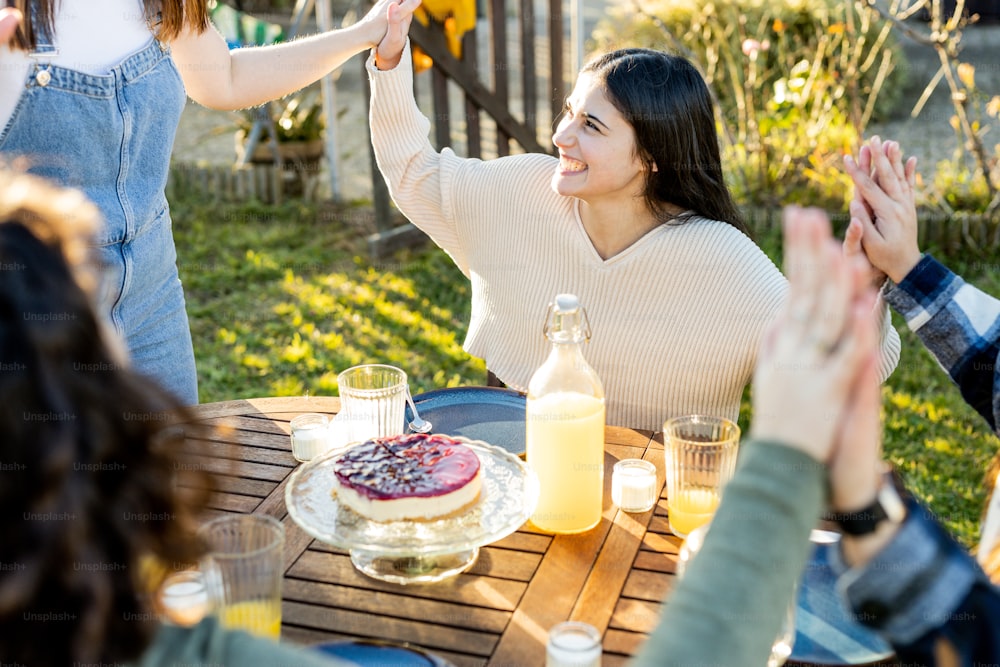 a group of people sitting around a table with a cake