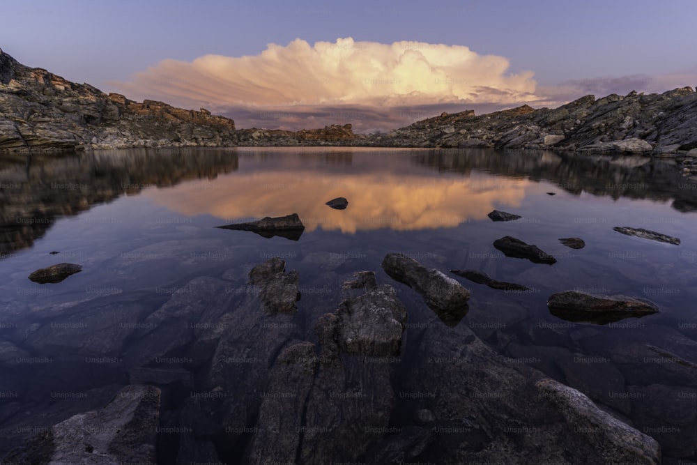 um lago cercado por rochas sob um céu nublado