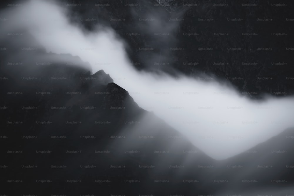 a black and white photo of mountains and clouds