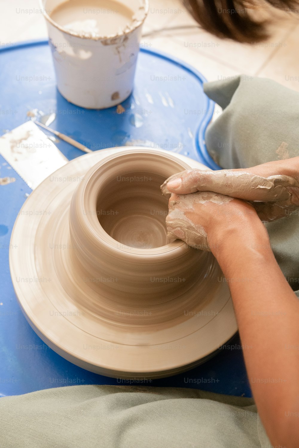 Una persona está haciendo un jarrón en una rueda de cerámica