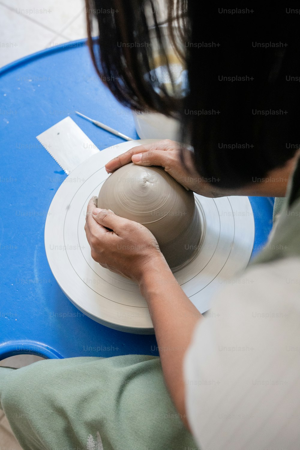 a woman is making a vase out of clay