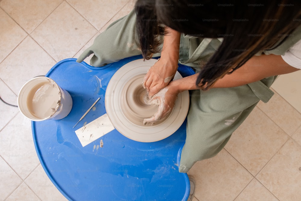 a woman sitting on a blue table making a bowl