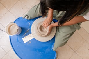 Une femme assise sur une table bleue en train de préparer un bol