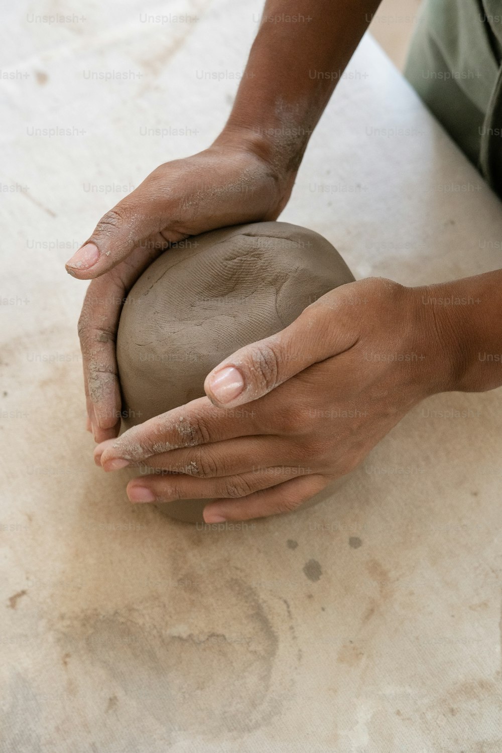 uma pessoa segurando uma bola de argila em suas mãos