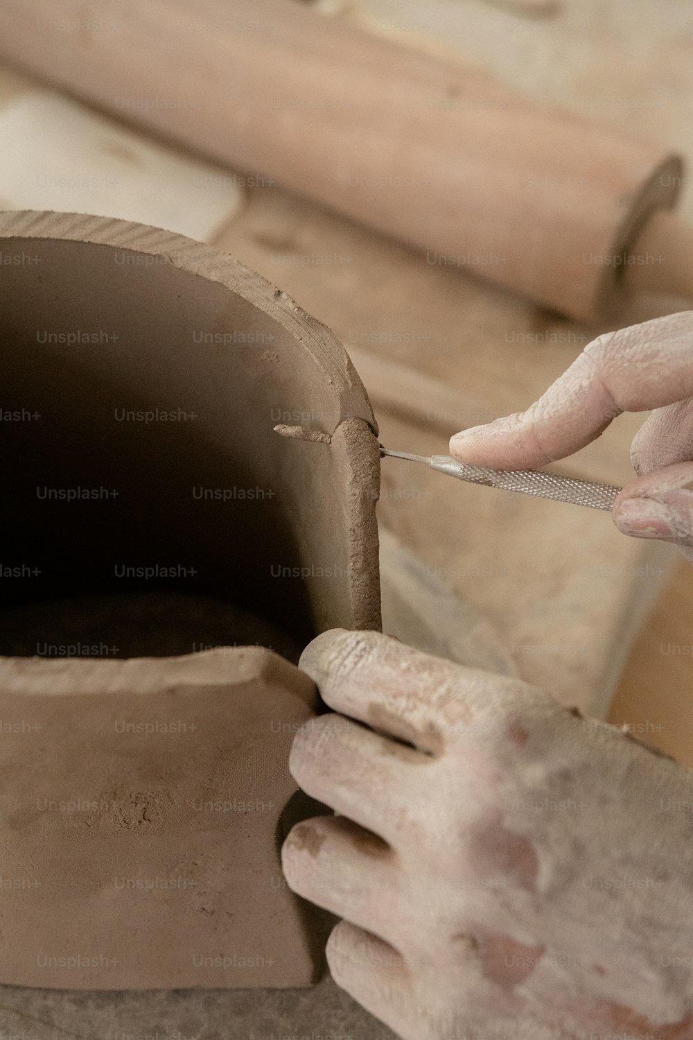 a person using a knife to cut a piece of clay