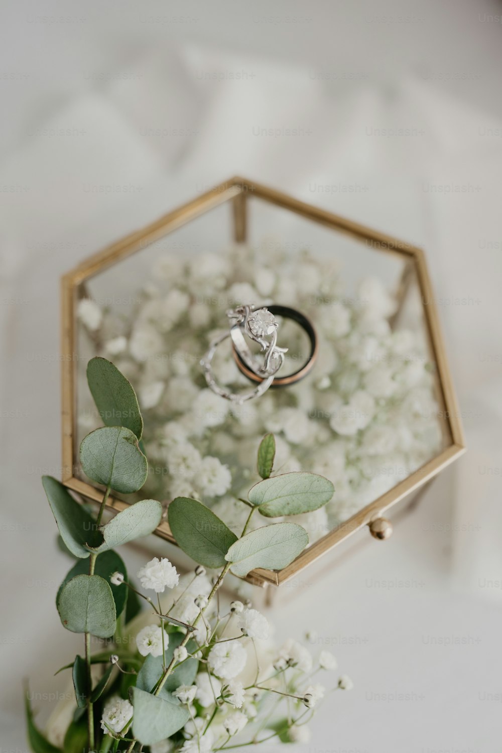 꽃다발 위에 앉아 있는 결혼 반지 두 개