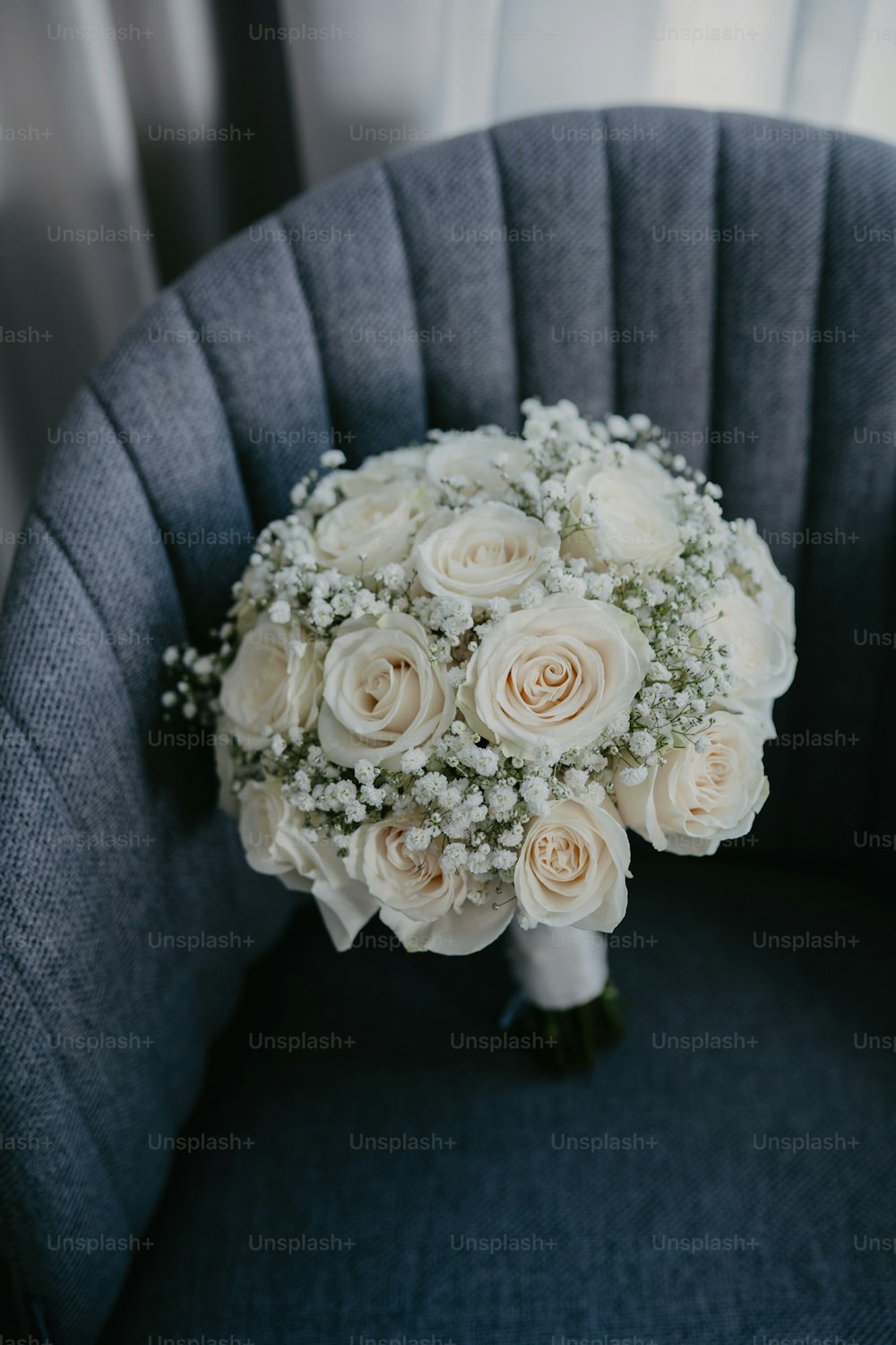 a bouquet of white roses sits on a chair
