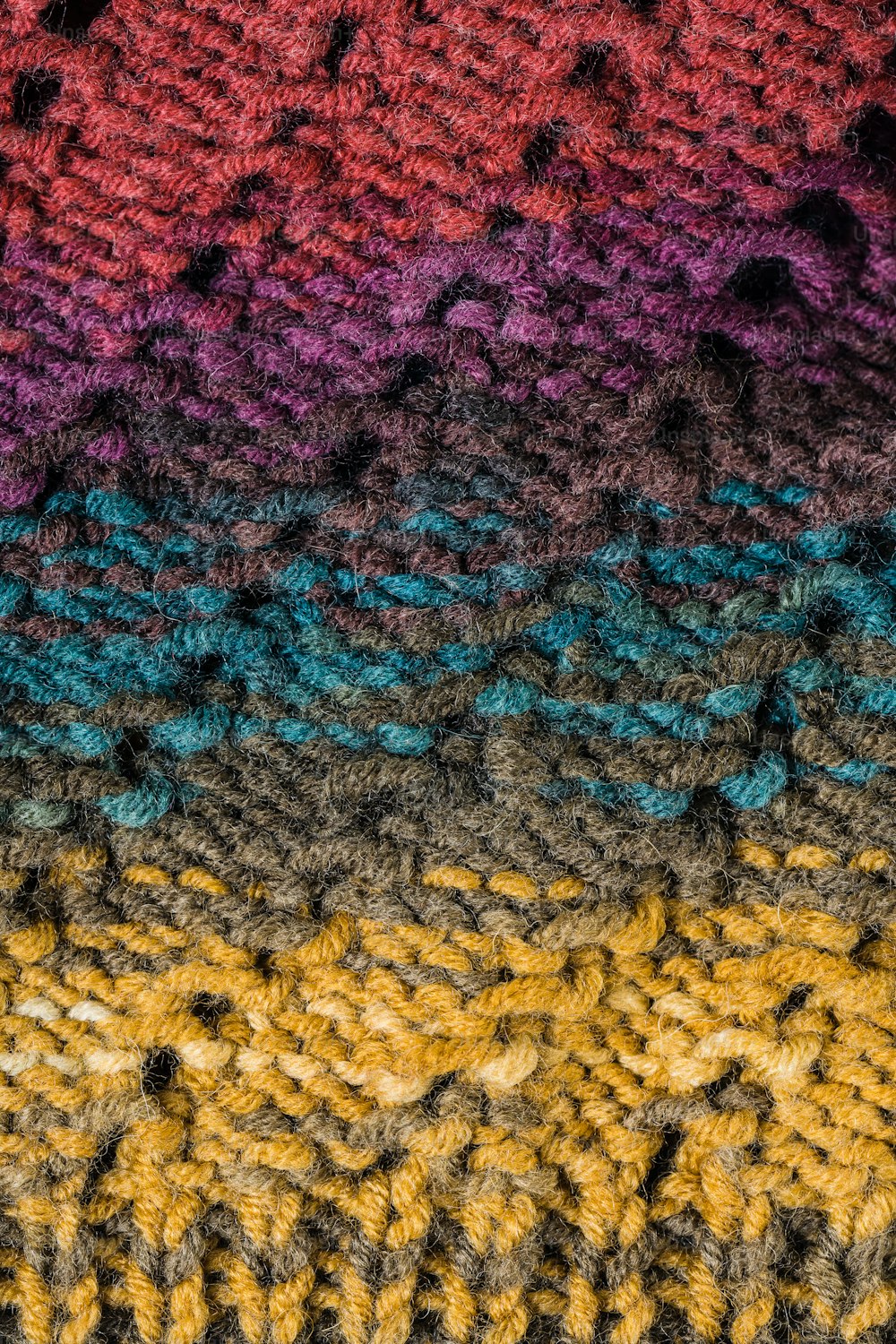 a multicolored crocheted blanket with a cell phone laying on top of