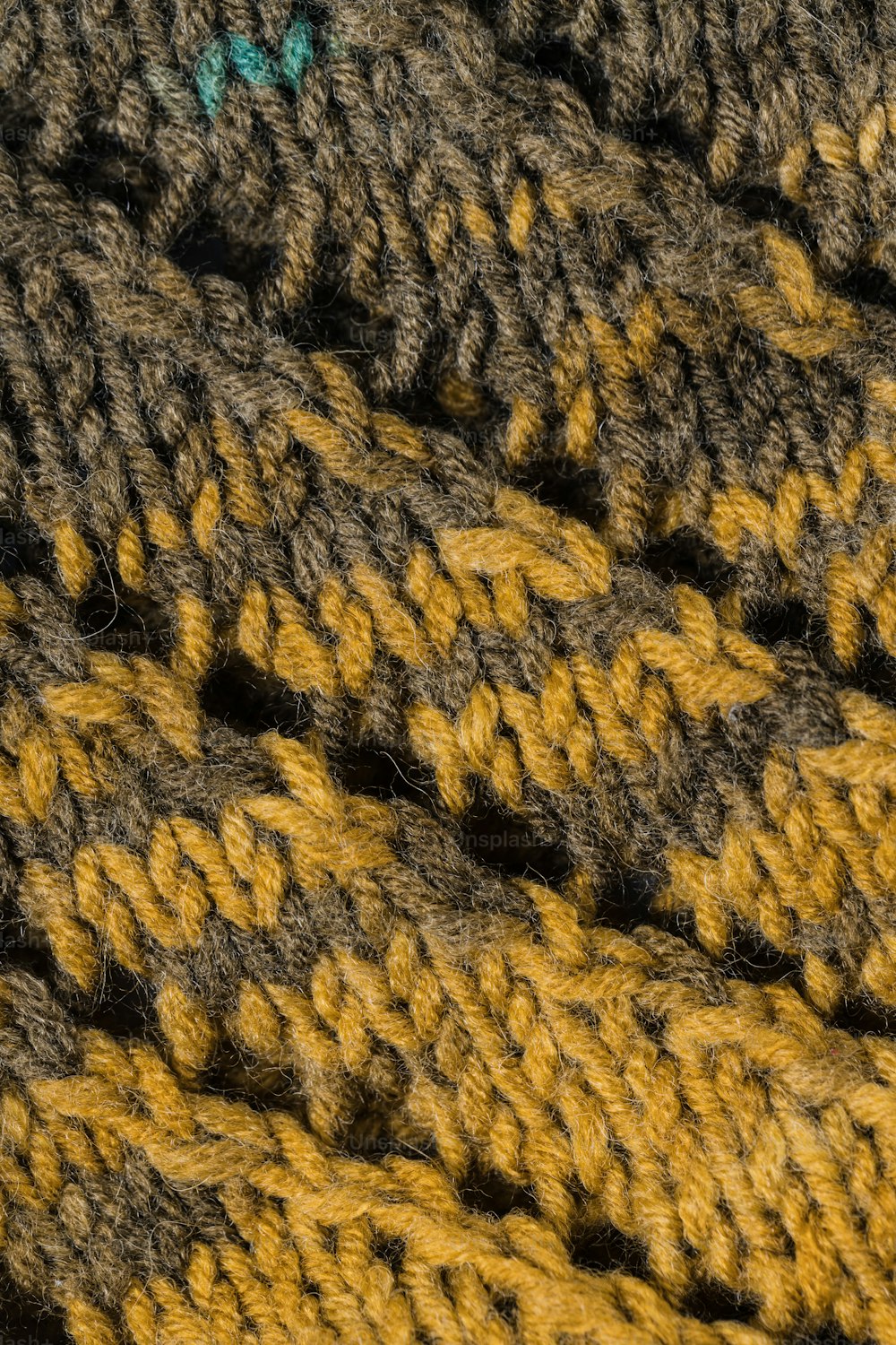 a close up of a crochet blanket with a green button