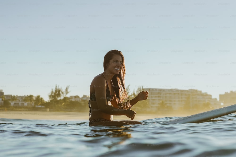 uma mulher sentada em uma prancha de surf na água