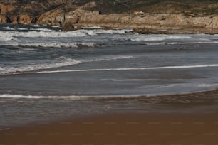 Eine Person, die mit einem Surfbrett am Strand spazieren geht