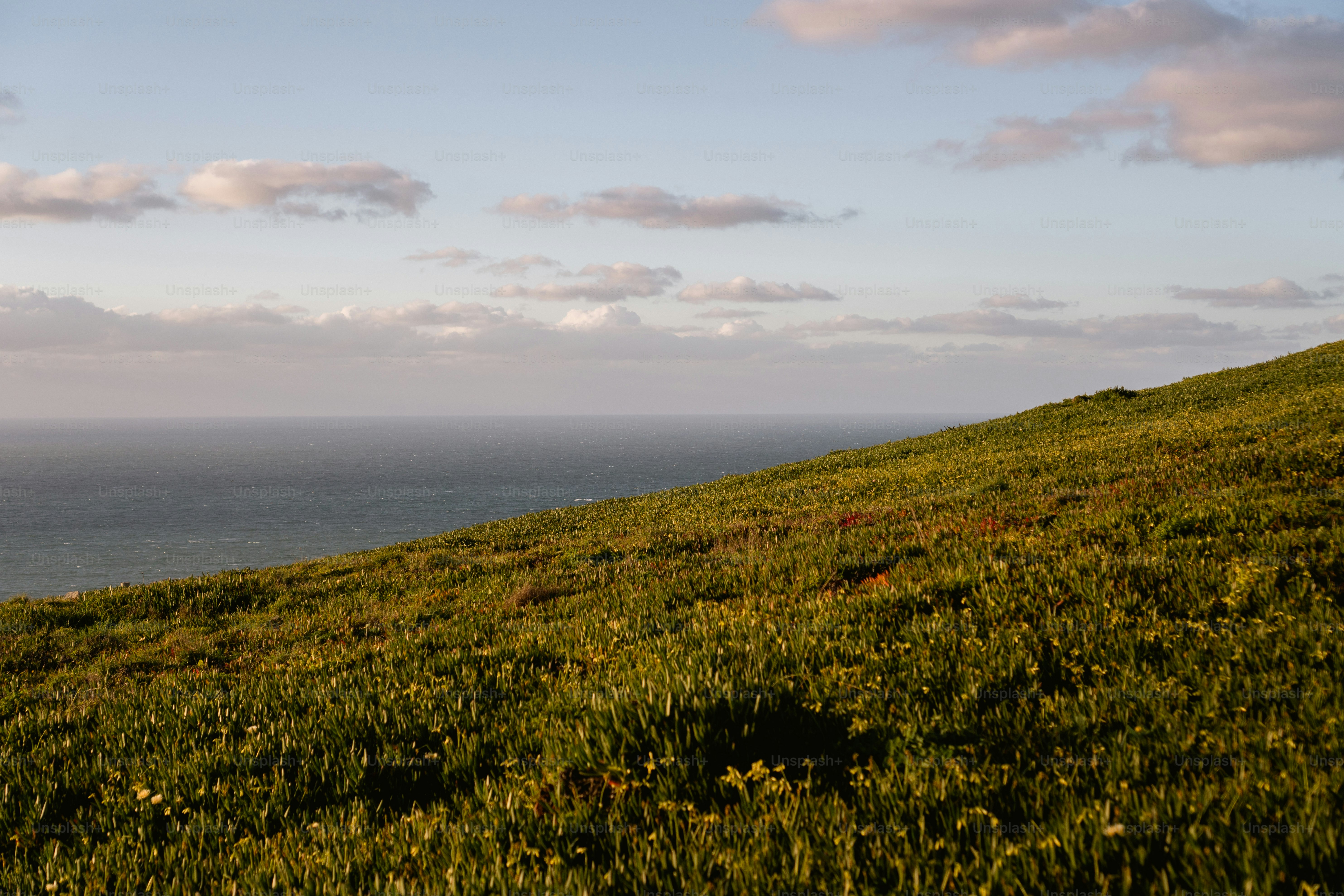 una collina erbosa con uno specchio d'acqua in lontananza