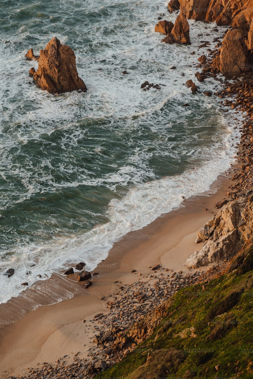 a sandy beach next to a rocky cliff