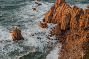 an aerial view of the ocean with rocks in the foreground