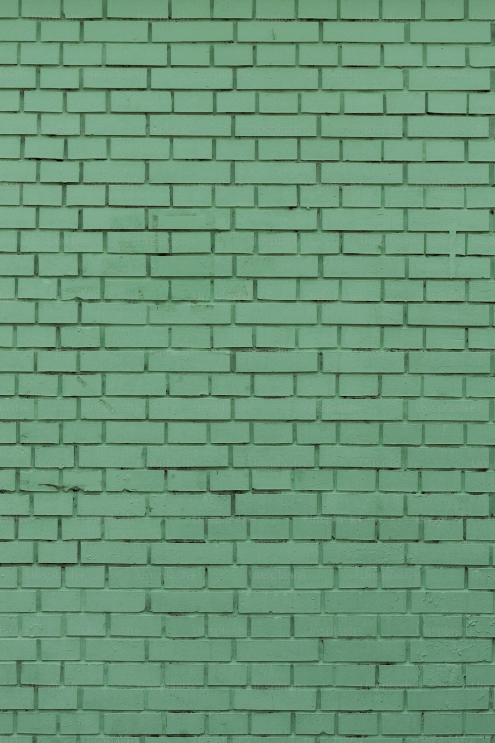 una pared de ladrillo verde con una boca de incendios roja