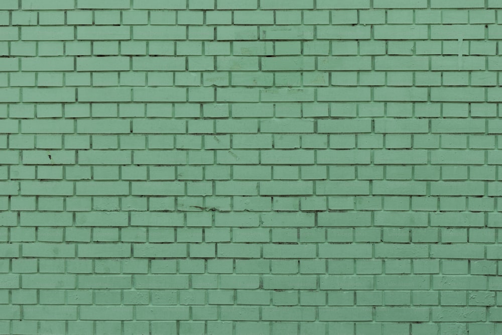 a green brick wall with a red fire hydrant