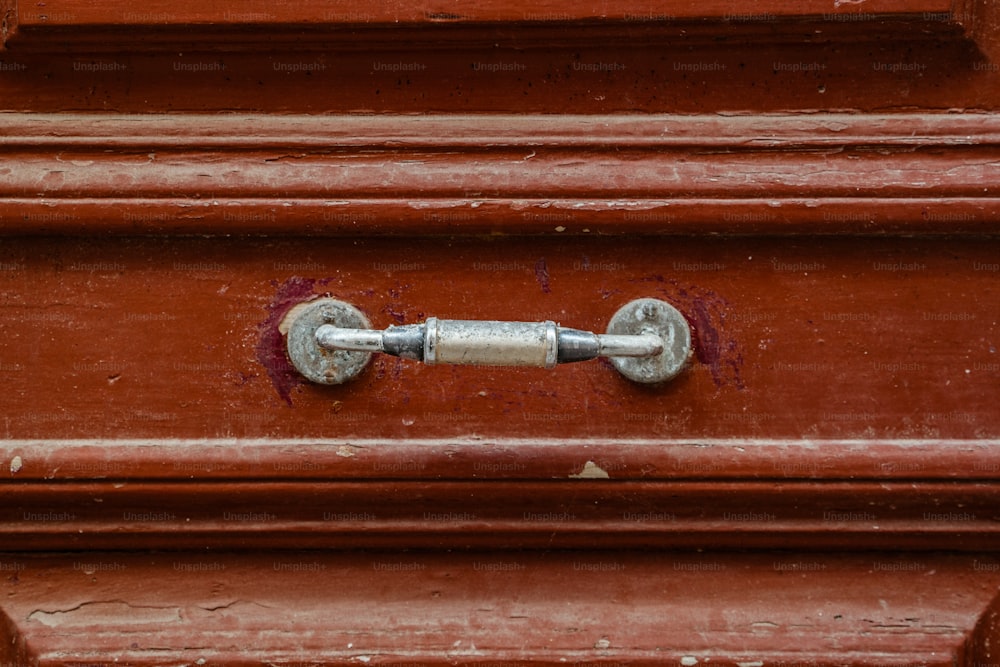 a close up of a metal handle on a red door