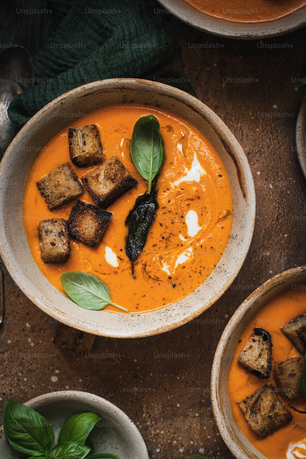 uma tigela de sopa de tomate com croutons e manjericão