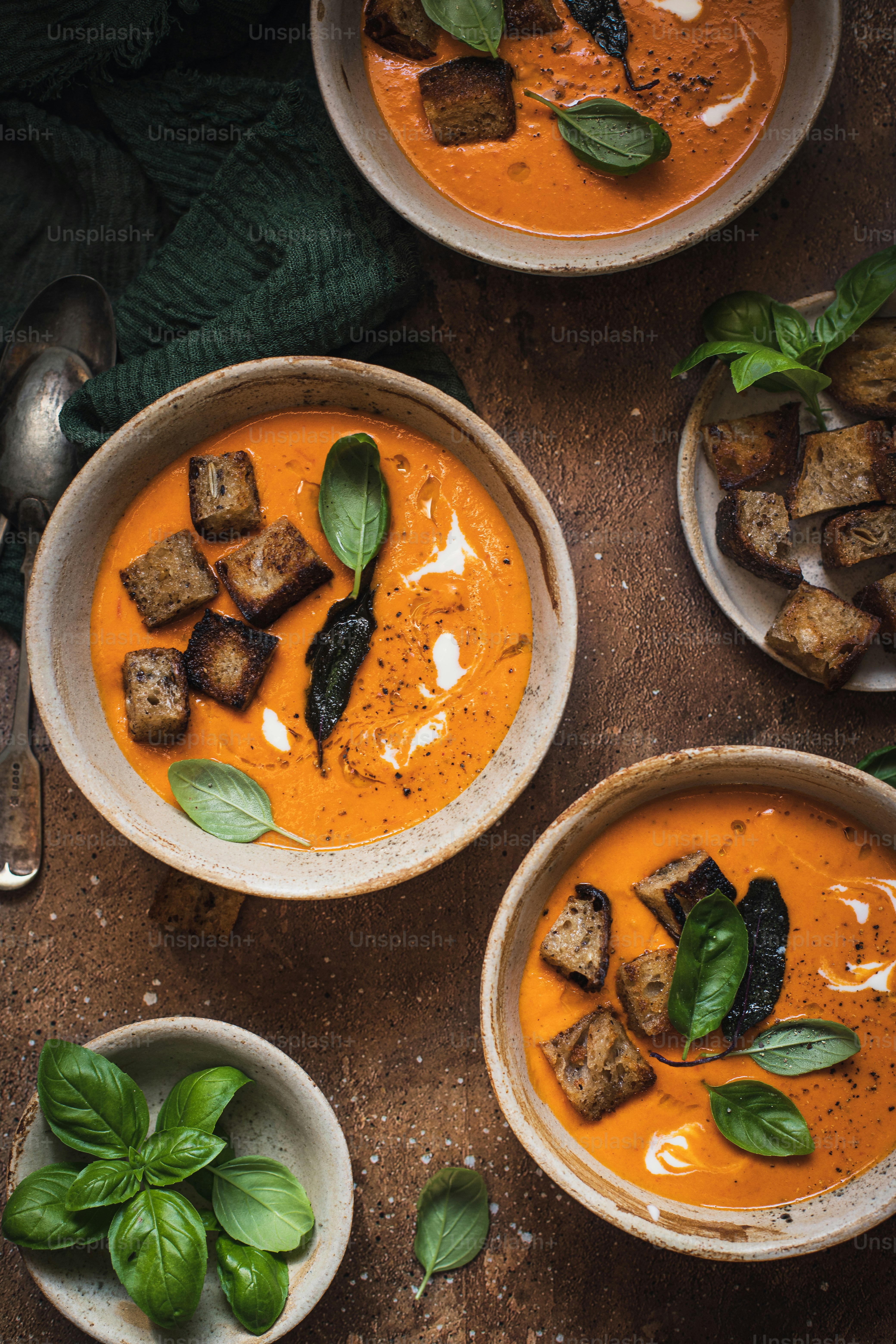 three bowls of tomato soup on a table