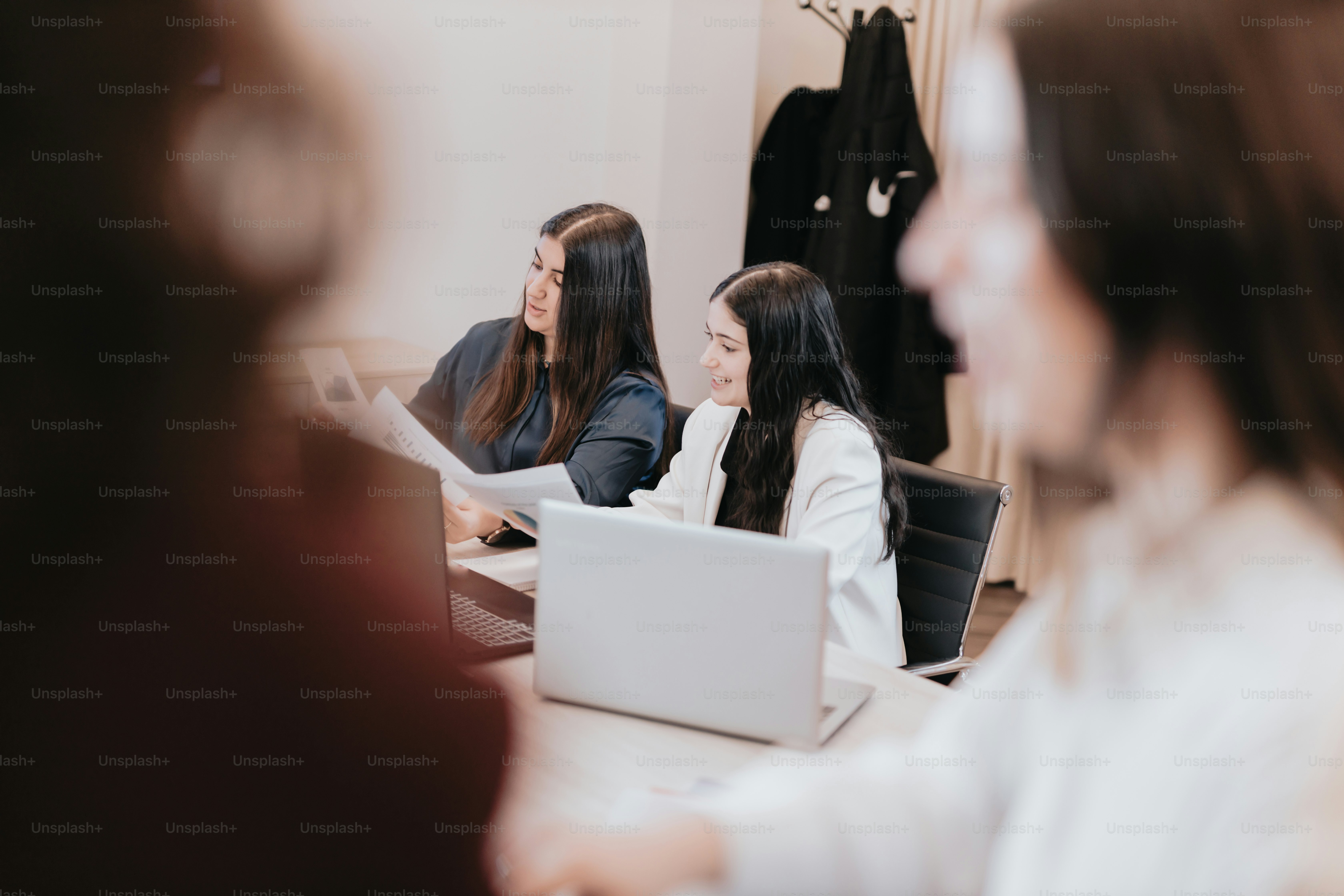 a group of women sitting at a table with laptops