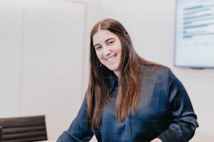 a woman sitting at a table smiling for the camera