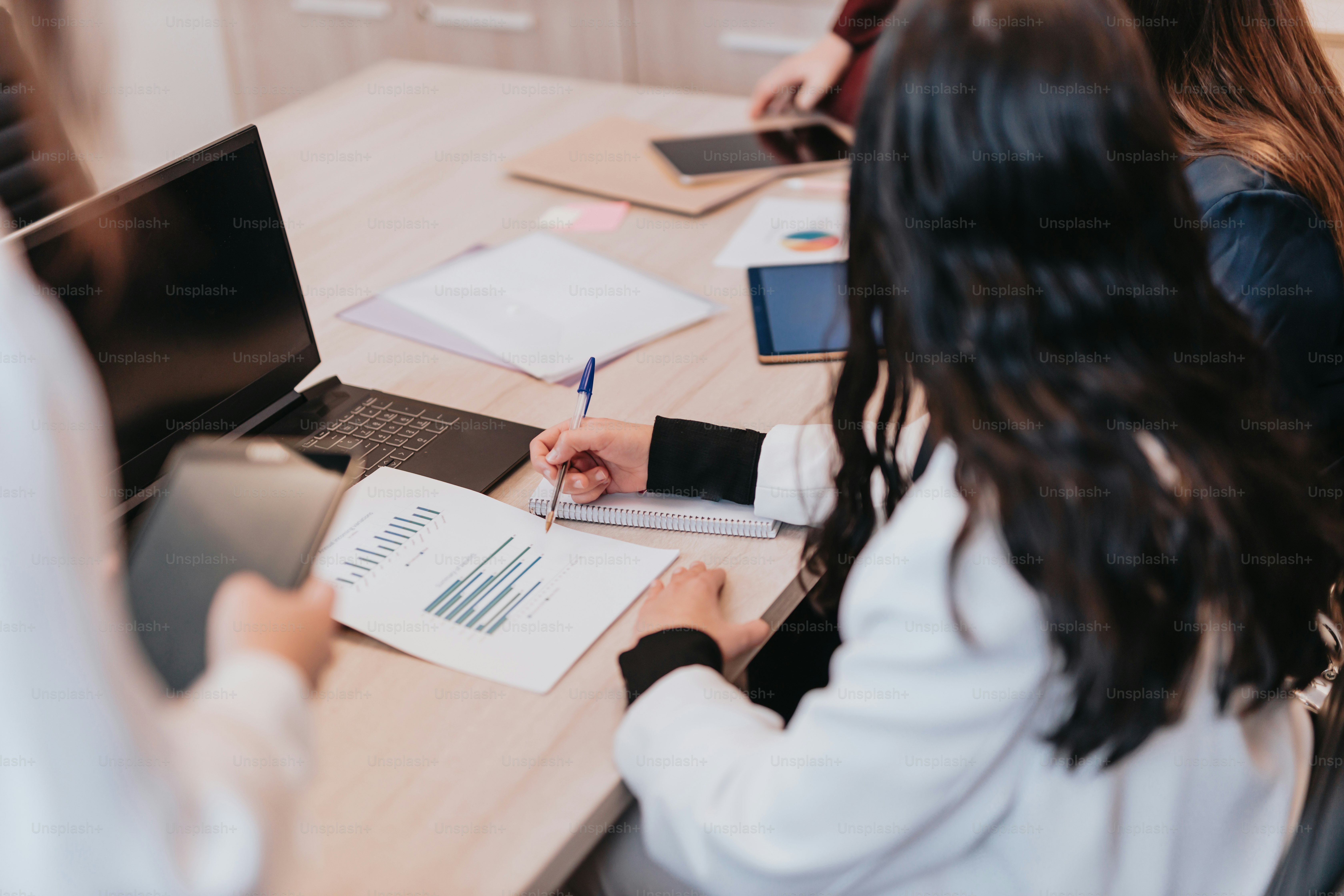 Un gruppo di persone sedute intorno a un tavolo con computer portatili