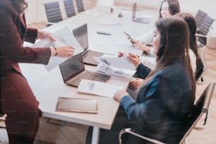 a group of people sitting around a table with laptops