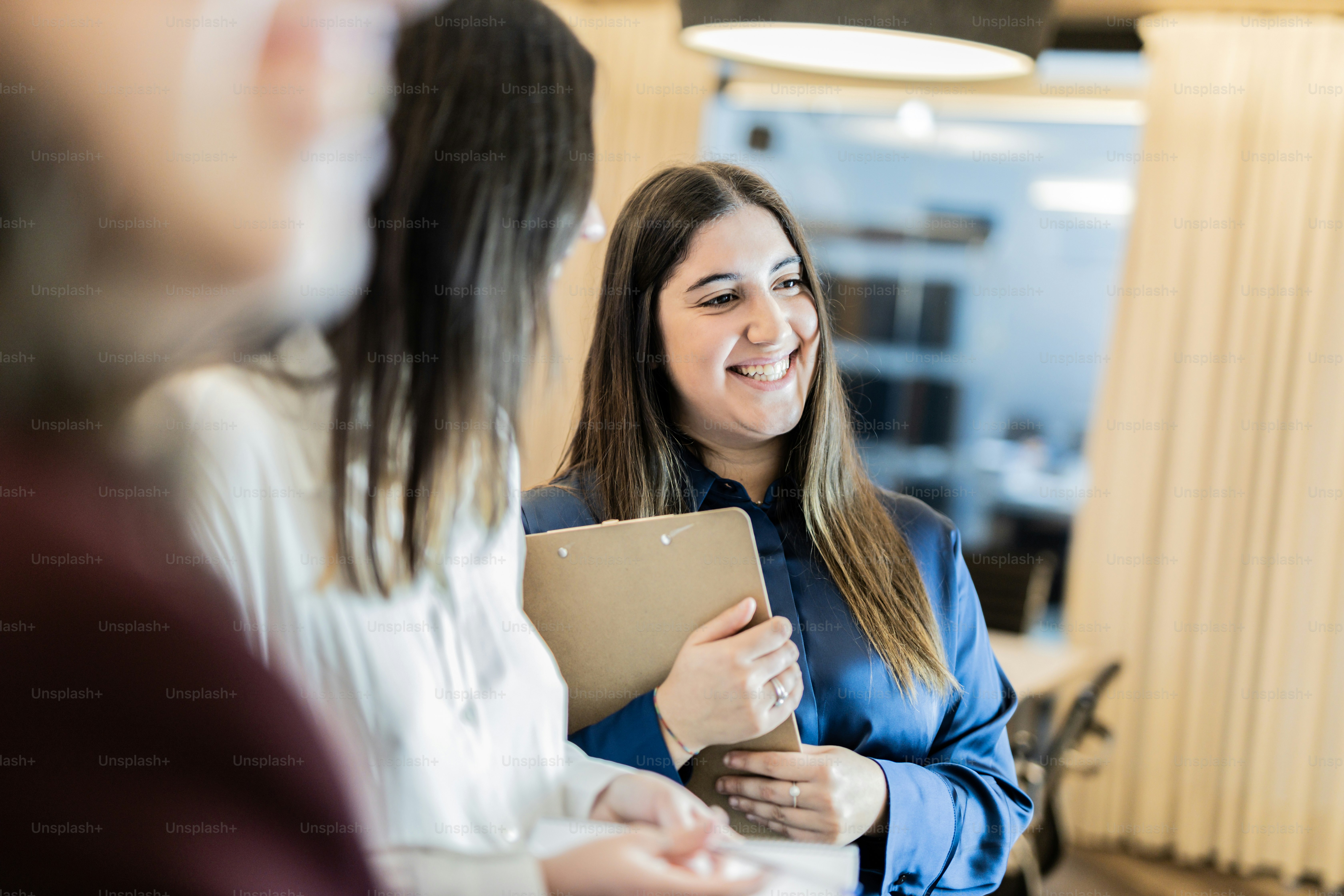 A woman is smiling and holding a folder photo – Corporate Image on Unsplash