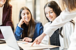 a group of women sitting around a laptop computer