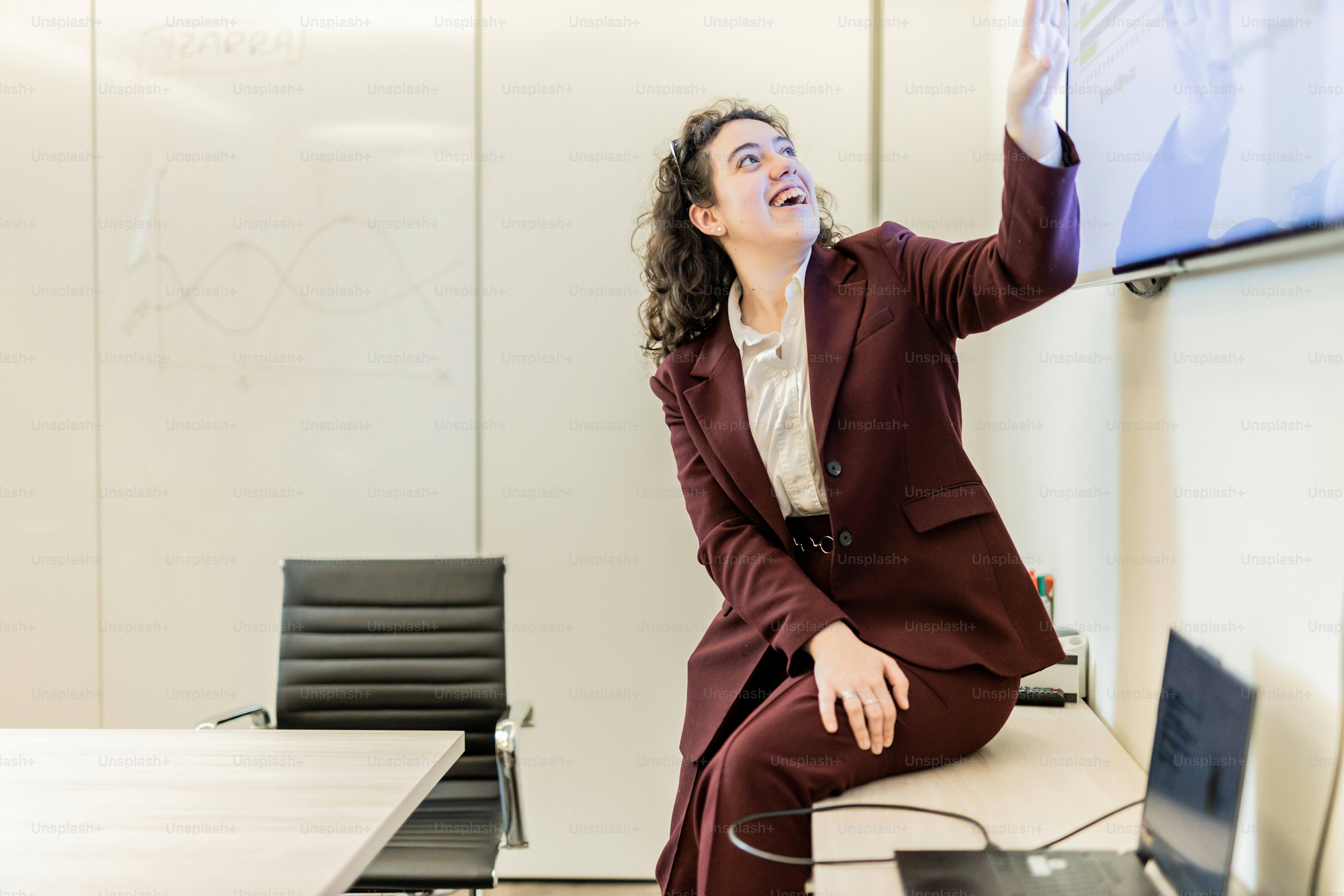 a woman in a suit sitting at a table with a laptop