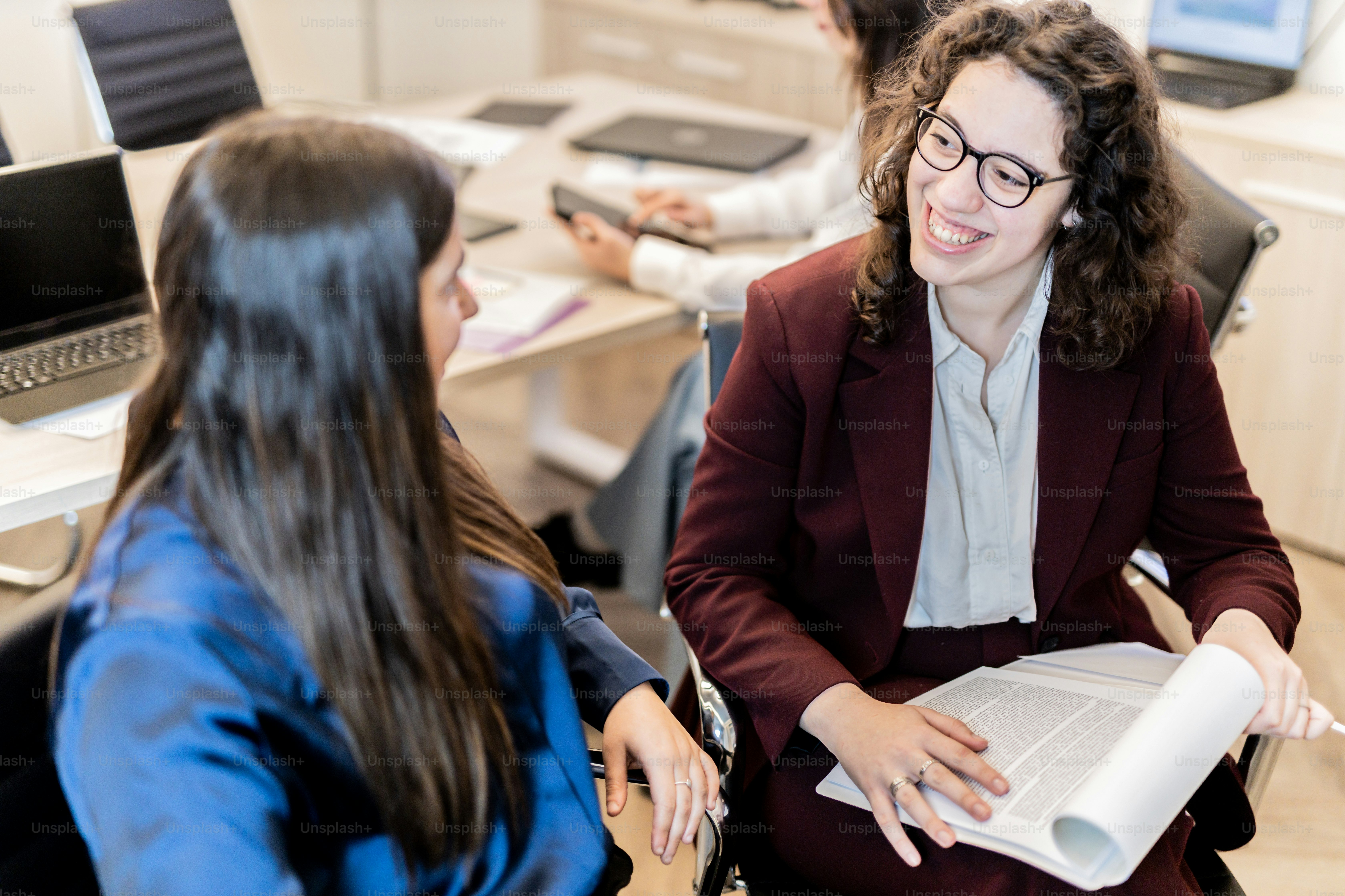 a woman sitting in a chair talking to another woman