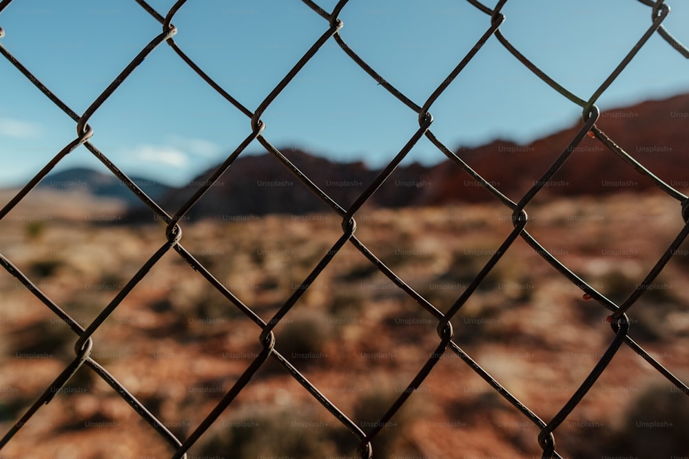 a close up of a fence with mountains in the background