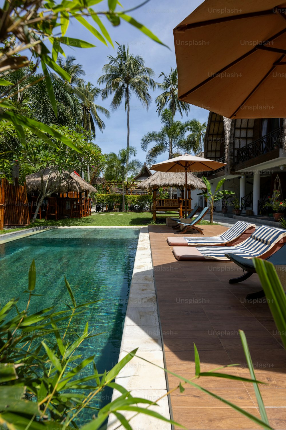 a pool with lounge chairs and umbrellas next to it