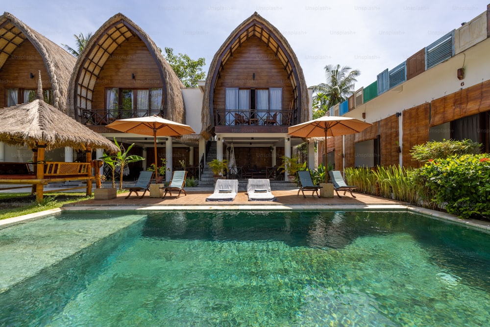 a pool with chairs and umbrellas in front of a house