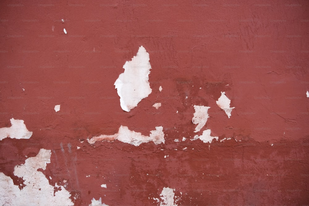 a red wall with peeling paint on it