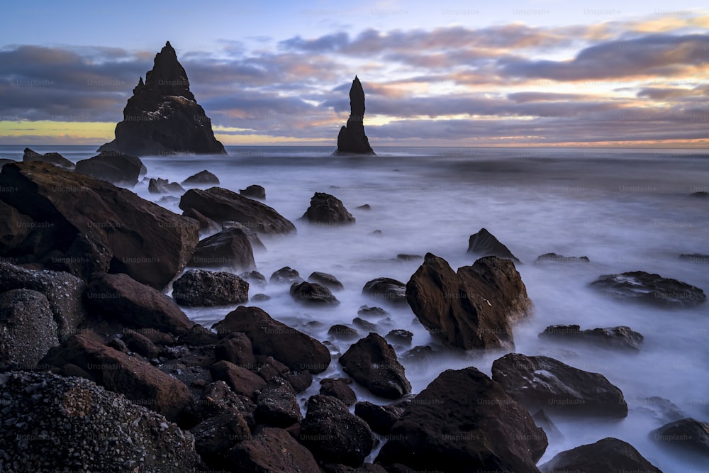 uma praia rochosa com grandes rochas em primeiro plano