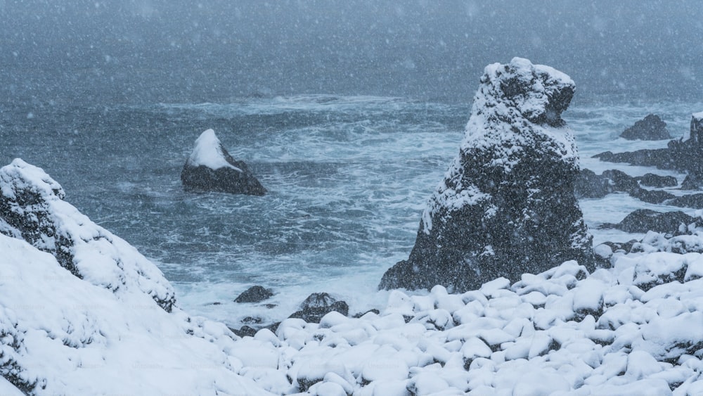 uma costa rochosa coberta de neve ao lado do oceano