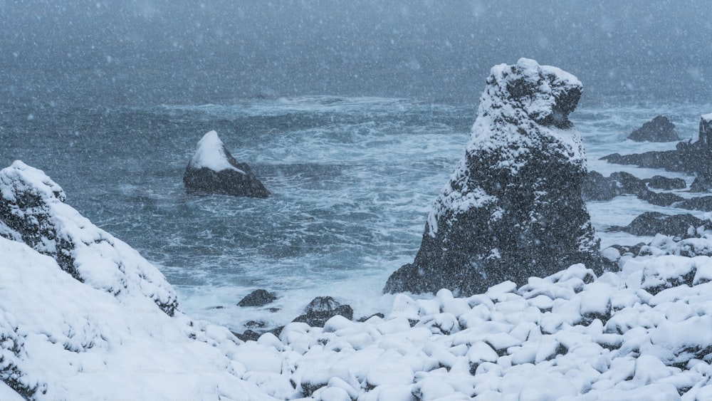 a rocky shore covered in snow next to the ocean