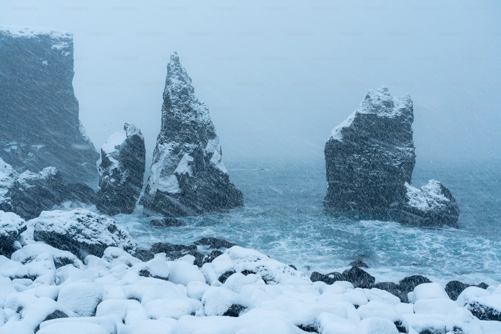 a rocky beach covered in snow next to the ocean