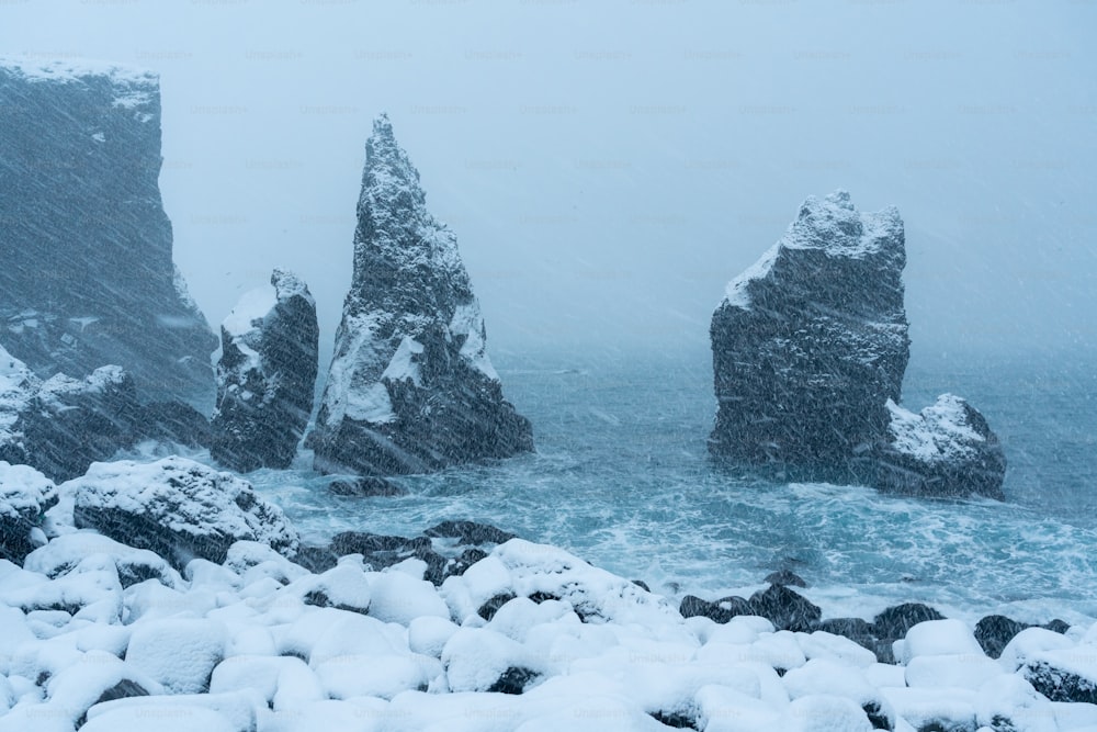 海の隣に雪に覆われた岩だらけのビーチ