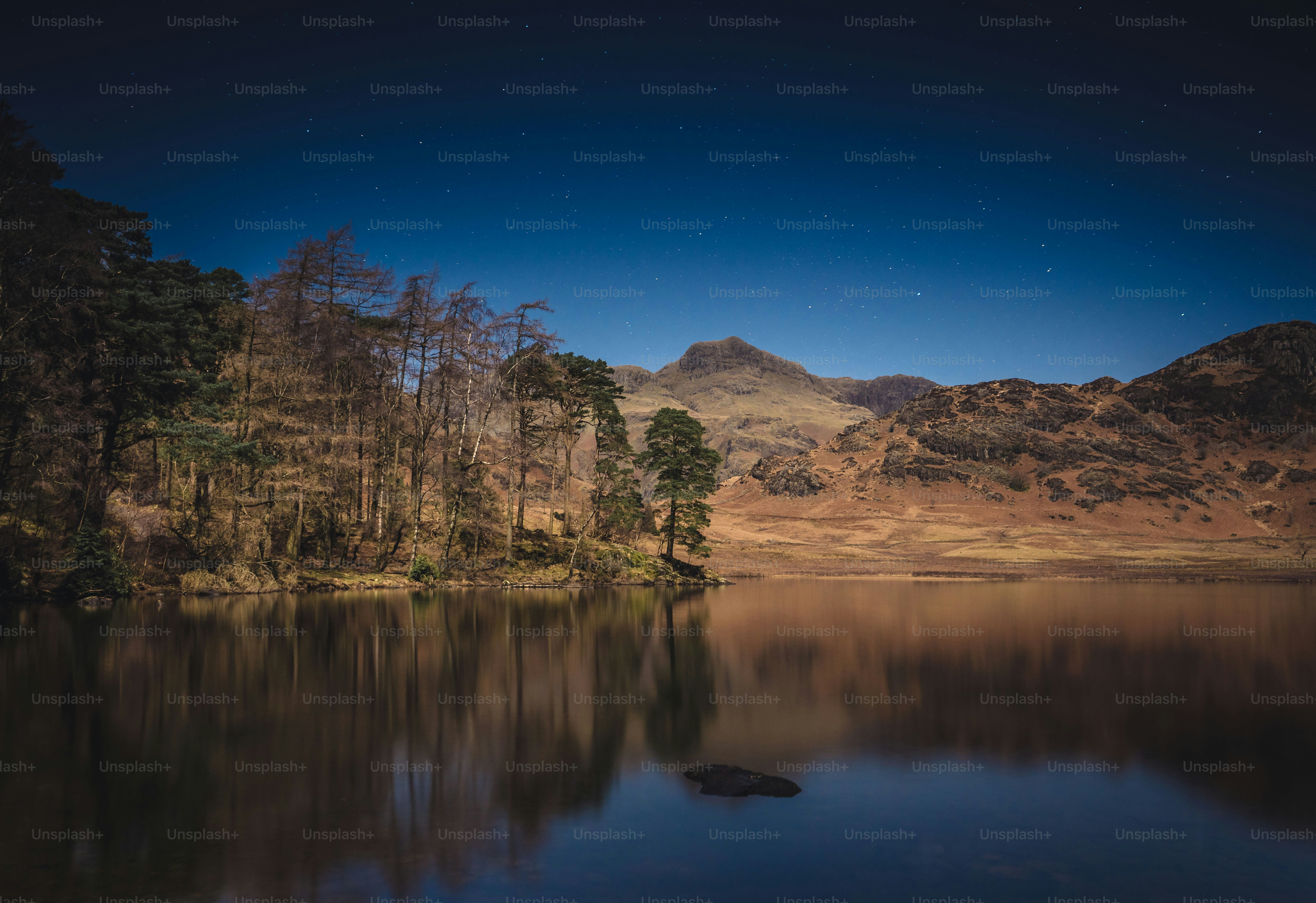 A lake surrounded by mountains under a night sky photo – Wallpapers ...