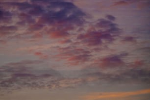 Un avion volant dans un ciel nuageux au coucher du soleil