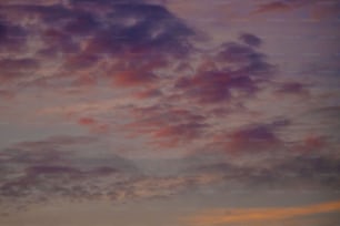 a plane flying through a cloudy sky at sunset