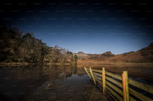 a wooden dock sitting next to a lake under a night sky