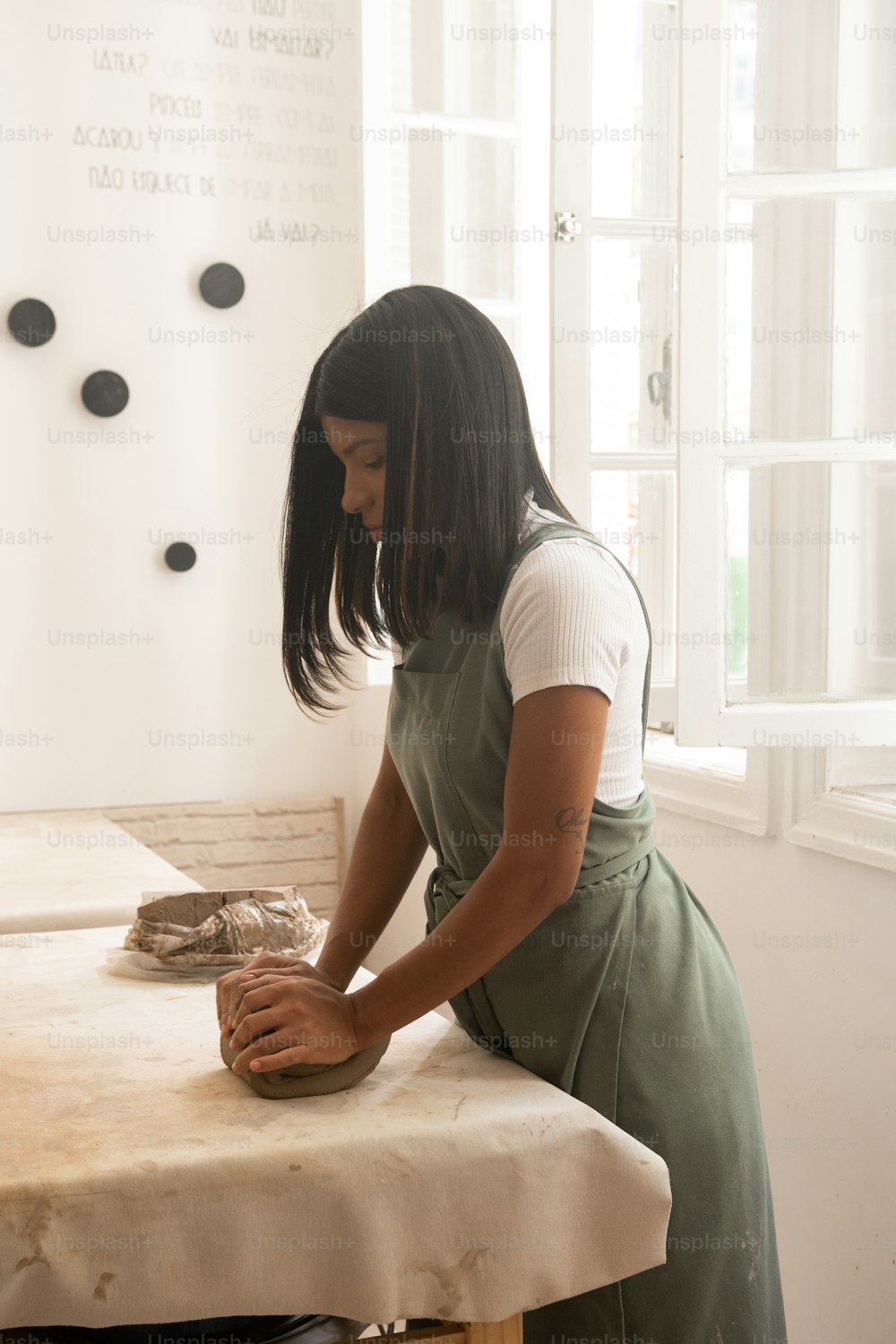 a woman in an apron is kneading something on a table