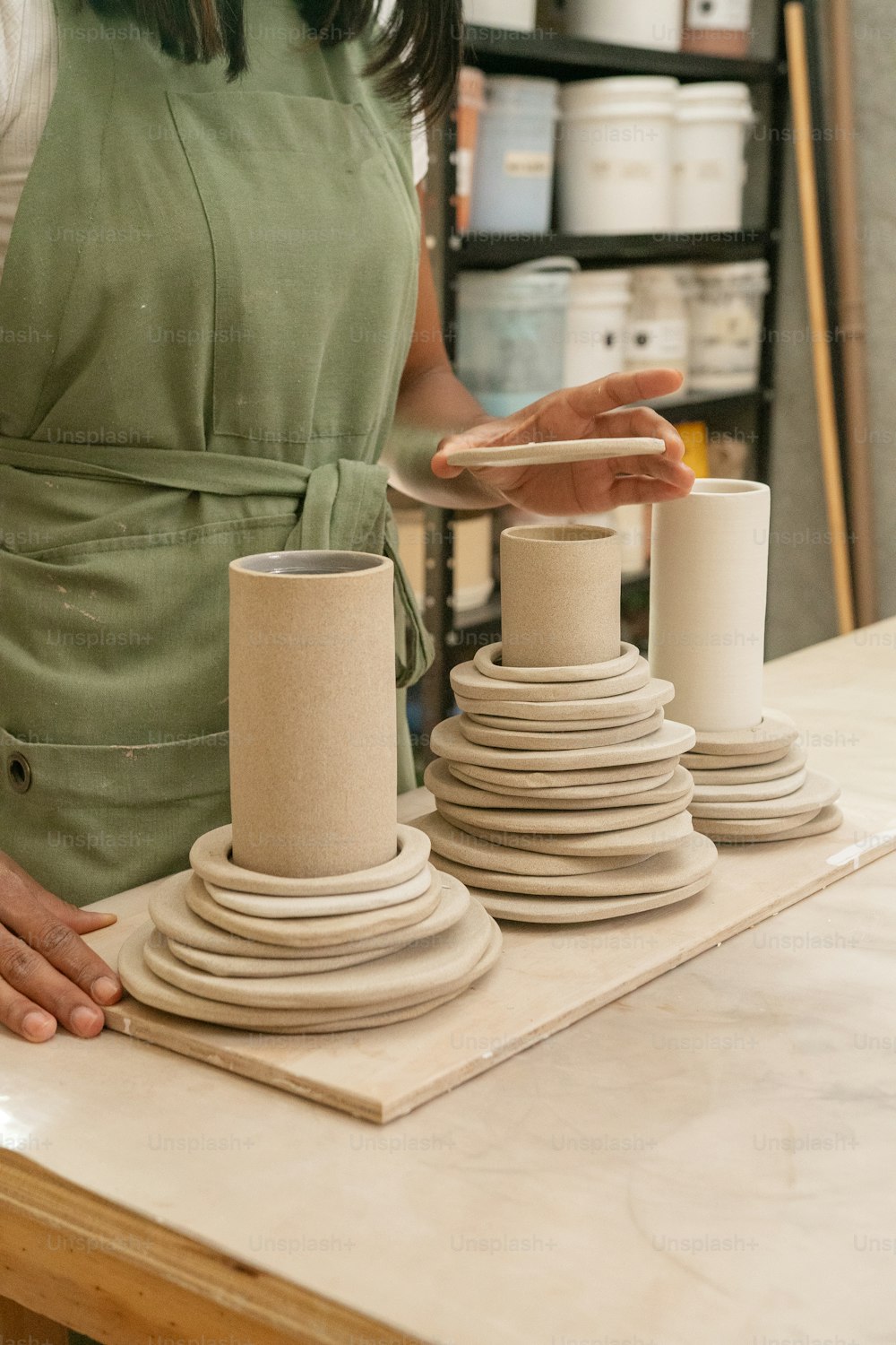 Une femme en robe verte fabrique des vases