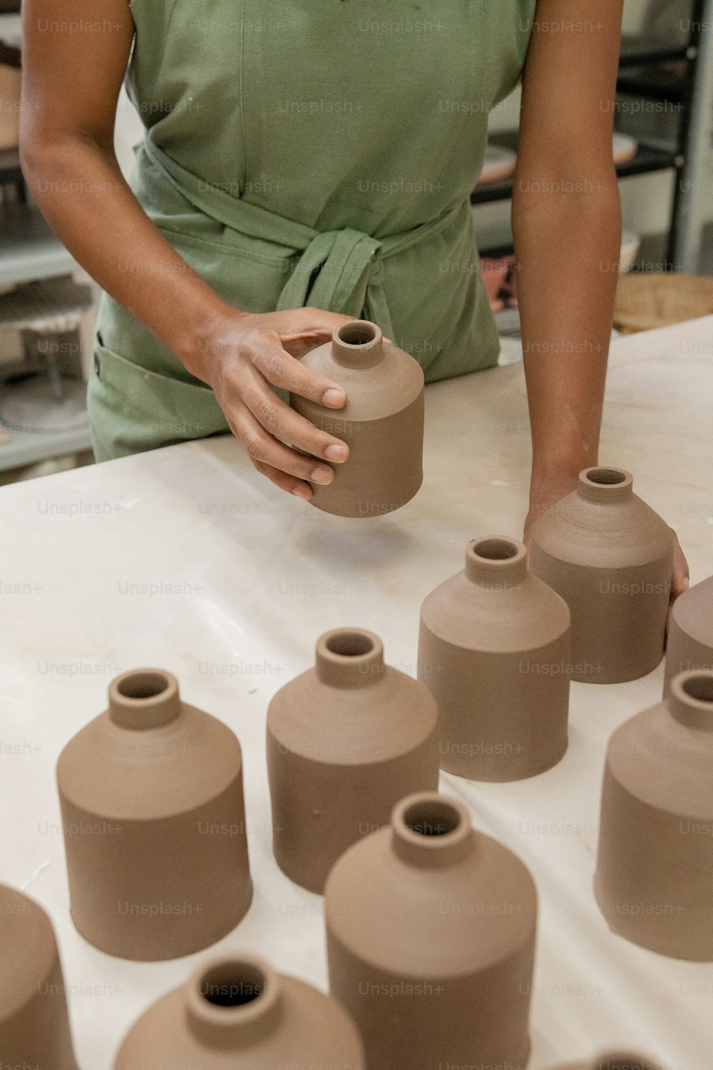 a woman is making vases out of clay