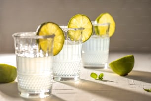 three glasses of water with limes on the side