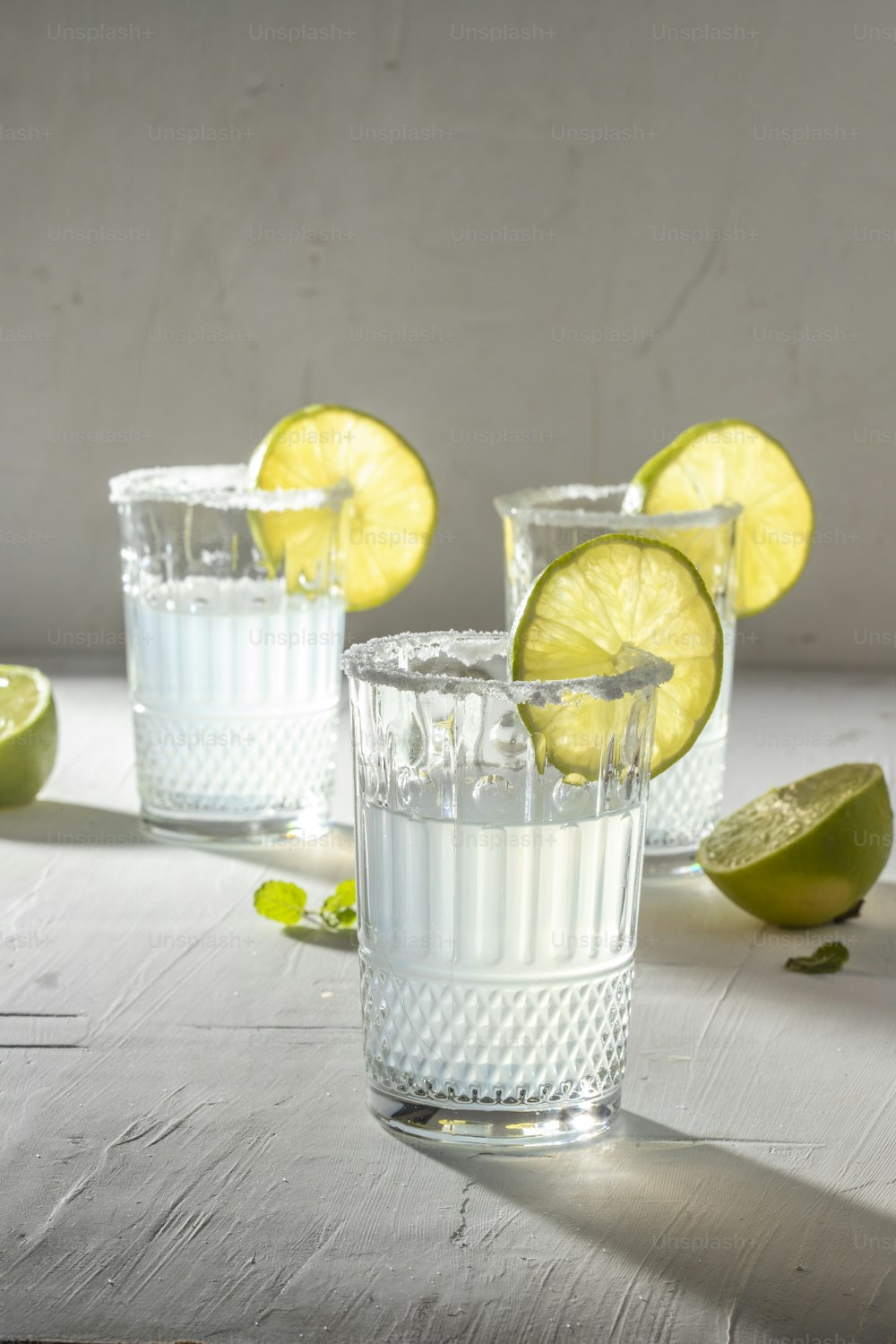 three shot glasses filled with lemonade and limes